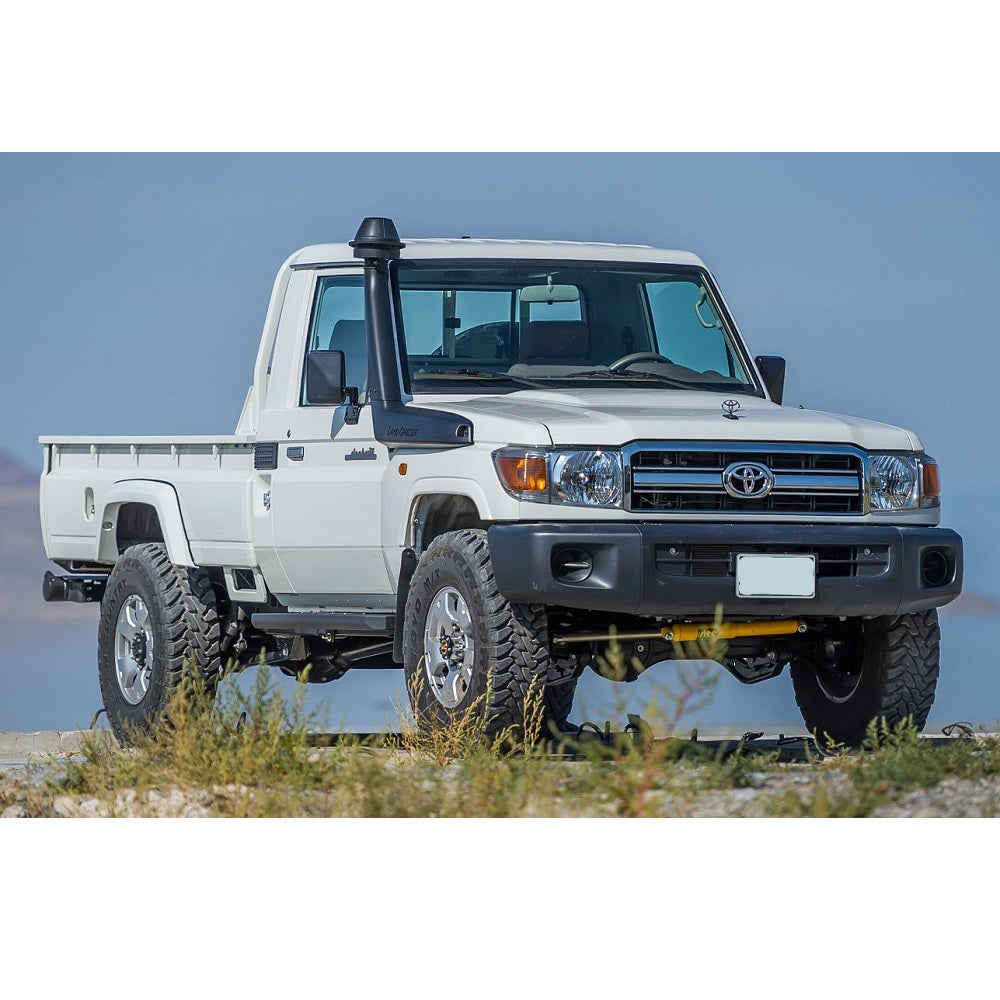 An Old Man Emu-equipped white Toyota Land Cruiser parked on a dirt road, showcasing the impressive OME 2.5 inch Lift Kit for Landcruiser 79 Series (2010-ON) suspension system and remarkable ground clearance.