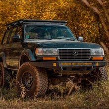 Load image into Gallery viewer, An SUV with Nitrocharger shocks and Old Man Emu OME 2 inch Lift Kit for Lexus LX450 (96-97) suspension system parked in the woods, providing increased ground clearance.