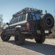 Load image into Gallery viewer, A black Toyota Land Cruiser with an Old Man Emu 2 inch Lift Kit for Lexus LX450 (96-97) suspension system and Nitrocharger shocks is parked on a dirt road, showcasing its increased ground clearance.