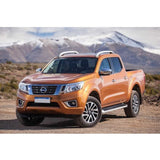The orange Old Man Emu Nissan Frontier showcases an impressive ground clearance as it is parked on a dirt road.