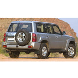 The rear end of a silver SUV with a high ground clearance on a dirt road, showcasing the Old Man Emu 2 inch Lift Kit for Patrol Y61 (99-09) suspension system.