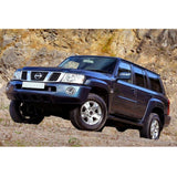 An Old Man Emu-equipped blue Nissan Armada with exceptional ground clearance and an OME 2 inch Lift Kit for Patrol Y61 (99-09) is parked in front of a rocky area.