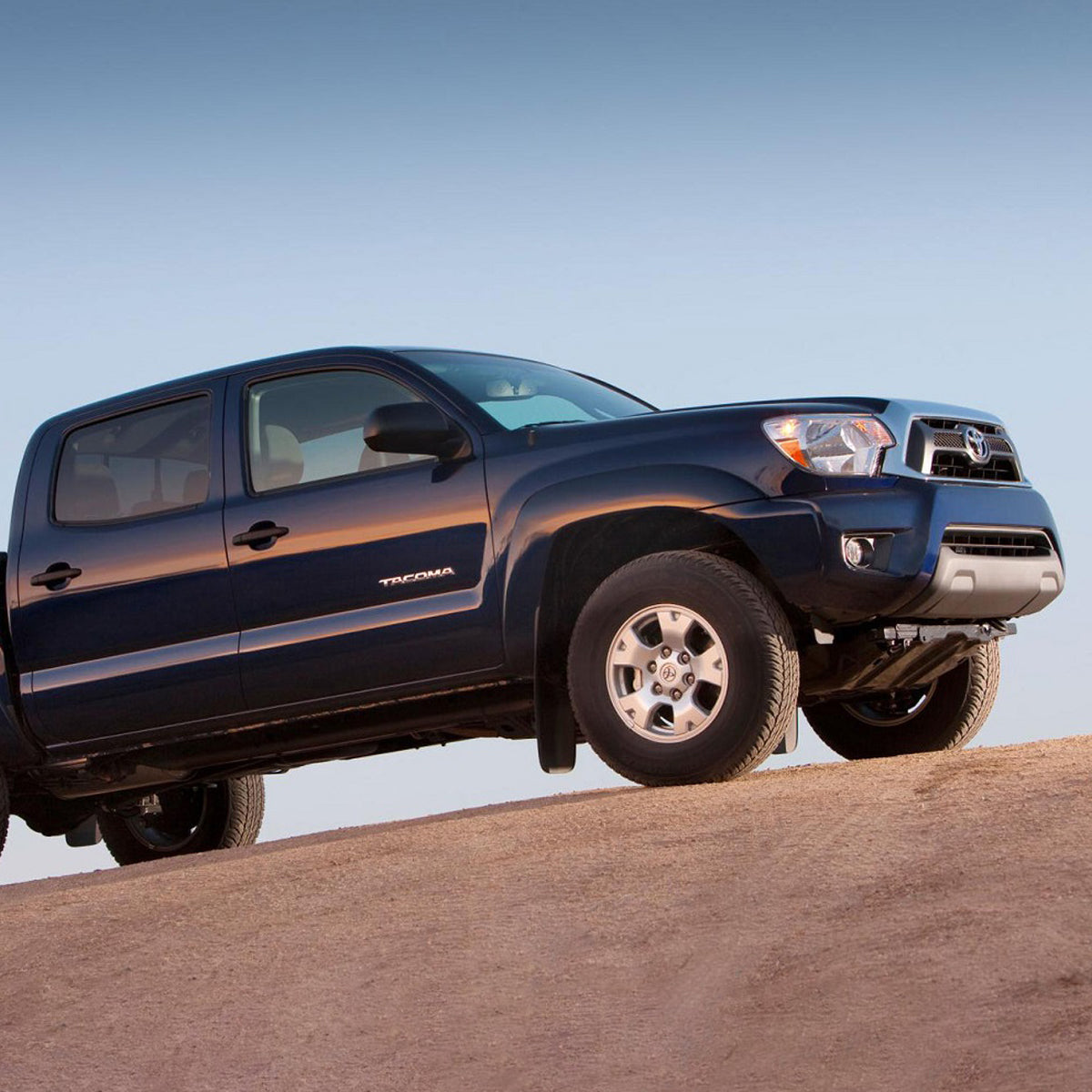 The 2013 Toyota Tacoma with the OME 2.5 inch Lift Kit for Tacoma (05-15) - Front Shocks Assembly from Old Man Emu is confidently maneuvering on a dirt road, showcasing exceptional ground clearance and suspension articulation.