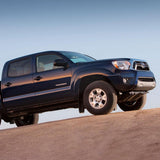The 2013 Toyota Tacoma with the OME 2.5 inch Lift Kit for Tacoma (05-15) - Front Shocks Assembly from Old Man Emu is confidently maneuvering on a dirt road, showcasing exceptional ground clearance and suspension articulation.