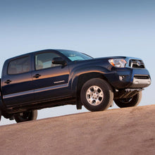 Load image into Gallery viewer, The 2013 Toyota Tacoma with the OME 2.5 inch Lift Kit for Tacoma (05-15) - Front Shocks Assembly from Old Man Emu is confidently maneuvering on a dirt road, showcasing exceptional ground clearance and suspension articulation.