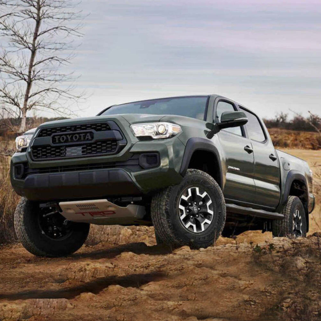 The 2019 Toyota Tacoma equipped with the OME 3 inch Essentials Lift Kit for Tacoma (16-23) by Old Man Emu demonstrates exceptional suspension articulation as it confidently maneuvers through the rugged terrain of a dirt road, thanks to its state-of-the-art Old Man Emu suspension system and ample ground clearance.