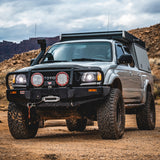 A Toyota Tacoma with an Old Man Emu OME 2 inch Lift Kit for Tacoma (98-04) parked on a dirt road, showcasing increased ground clearance and enhanced suspension articulation.
