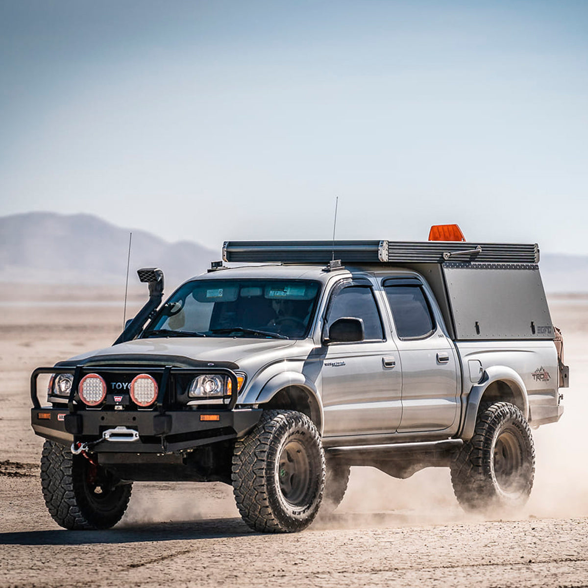 A Toyota Tacoma equipped with an OME 2 inch Lift Kit for Tacoma (98-04) from Old Man Emu drives through the desert, benefiting from increased ground clearance and enhanced suspension articulation.