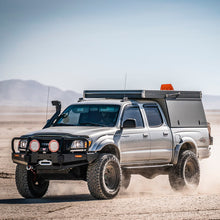 Load image into Gallery viewer, A Toyota Tacoma equipped with an OME 2 inch Lift Kit for Tacoma (98-04) from Old Man Emu drives through the desert, benefiting from increased ground clearance and enhanced suspension articulation.