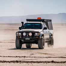Load image into Gallery viewer, An Old Man Emu 2 inch Lift Kit for Tacoma (98-04) pickup truck with an increased ground clearance driving through the desert.
