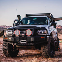 Load image into Gallery viewer, An Old Man Emu 2 inch Lift Kit for Tacoma (98-04) parked in the desert with increased ground clearance and enhanced suspension articulation.