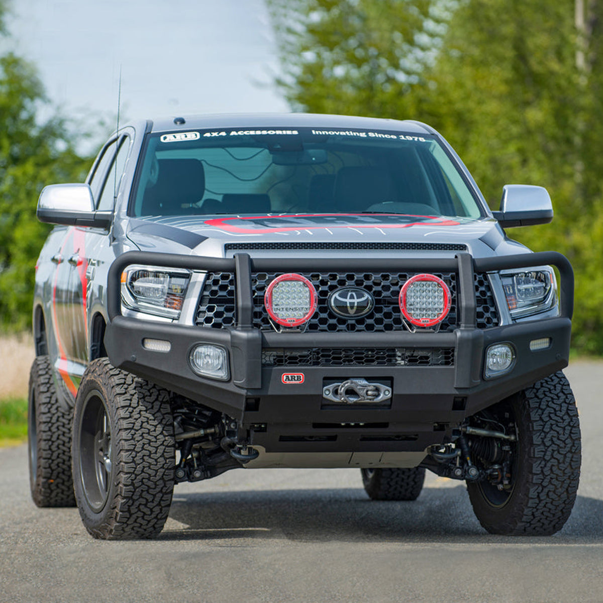 A Toyota Tacoma equipped with an Old Man Emu 2.5 inch Lift Kit for Tundra (07-21) is driving down a country road, smoothly and comfortably absorbing the uneven terrain with its Nitrocharger shocks.