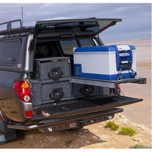 Load image into Gallery viewer, A water resistant ARB Outback Solutions Roller Drawer &amp; Roller Floor RDRF945 Toyota Hilux with a cooler in the back, perfect for off-road driving adventures.