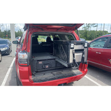 Load image into Gallery viewer, The ARB Outback Solutions Roller Drawer &amp; Roller Floor RDRF945 trunk of a red SUV equipped with maximum security, containing a laptop.