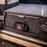 A truck with an ARB Roller Drawer Table RDTAB1355 storage compartment on top of it made of stainless steel.