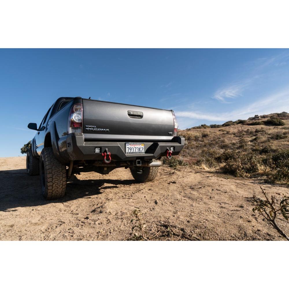 Body Armor 05-15 Toyota Tacoma Pro Series Rear Bumper in black steel with integrated shackle mounts on off-road terrain