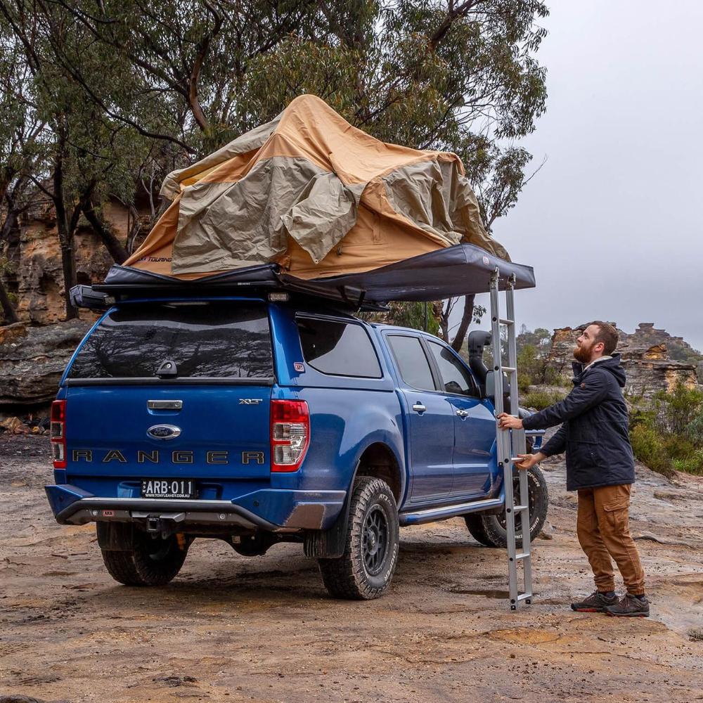 ARB Flinders Rooftop Tent 803300A mounted on blue 2021 Ford Ranger with off-road tires and aluminum ladder deployment
