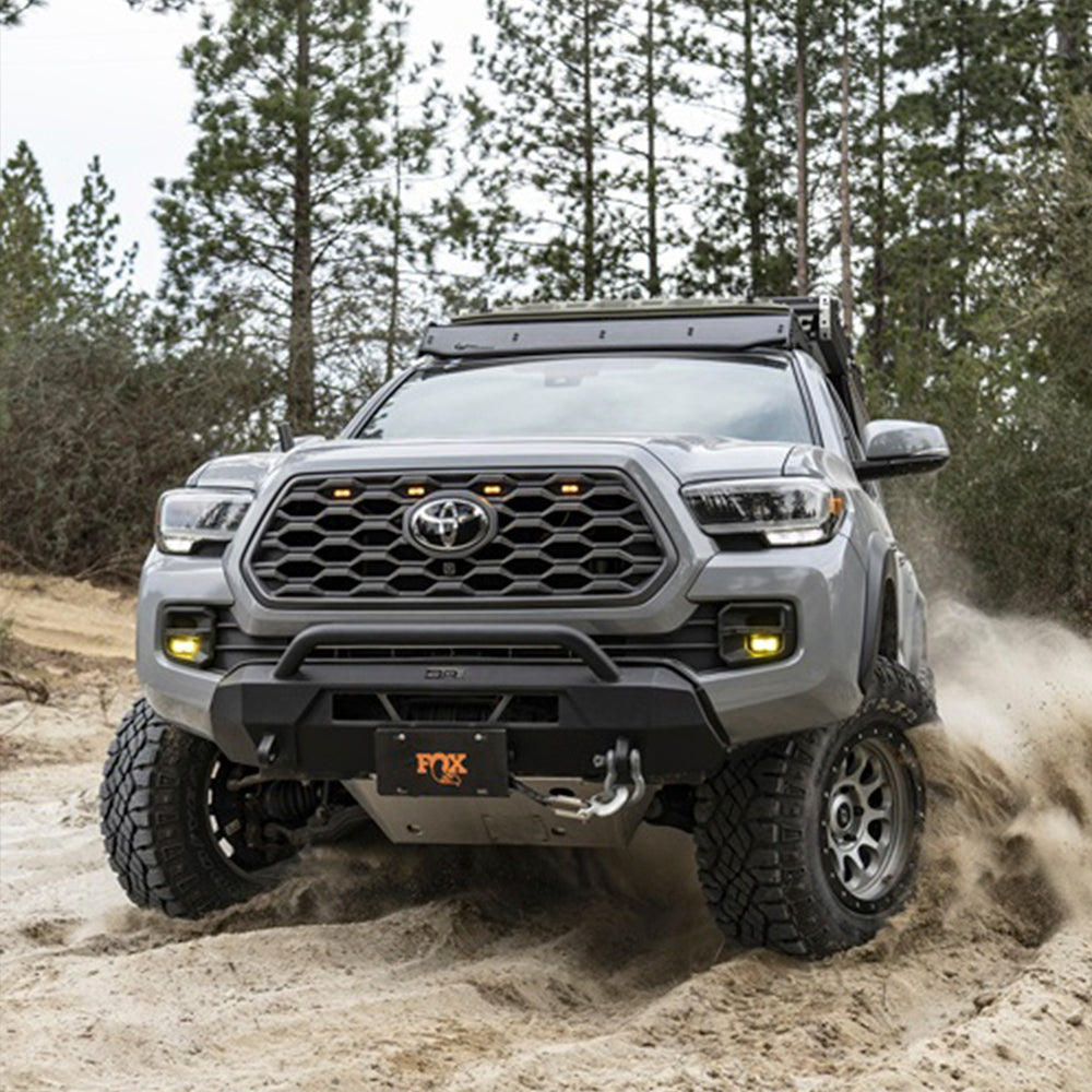 The 2019 Toyota Tacoma with its seamless steel body is driving through the woods, showcasing the long lasting finish of the FOX Front Factory Race Coil-Over Reservoir Shock 880-02-418 for Toyota Tacoma (Pair) from Fox Racing.