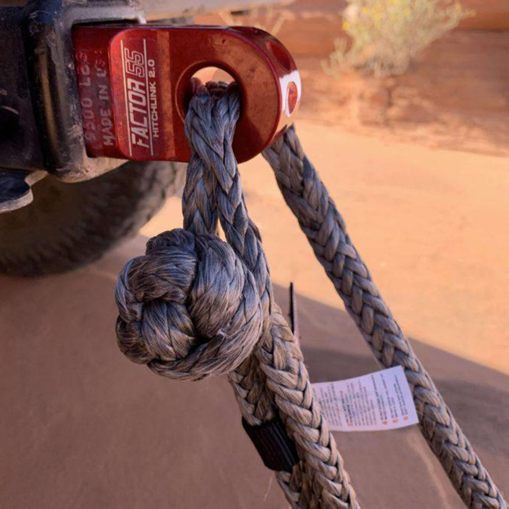 A Factor 55 HitchLink 2.0in Red 00020-01, a lightweight precision CNC machined rope with a 9500 pounds capacity, attached to the back of a jeep.