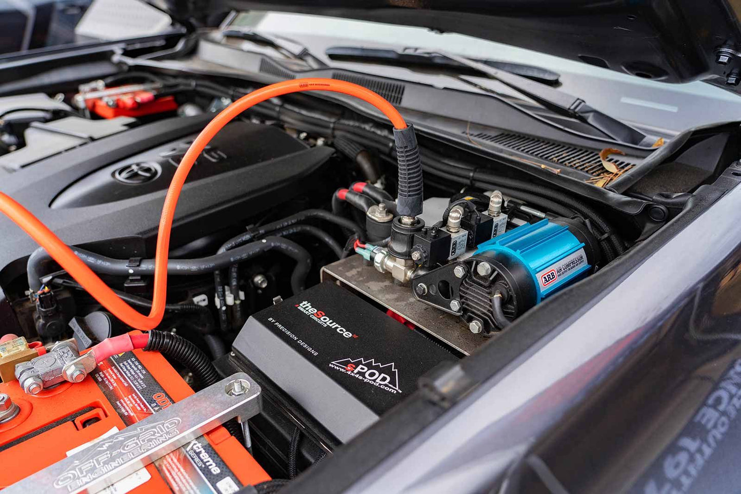 A car with the CKMTA12 Bundle Kit - ARB Inflation Kit, Air Compressor, and Digital Tire inflator in the hood.