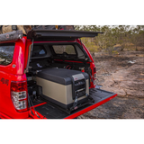 A gun-metal colored Toyota Hilux equipped with Bluetooth connectivity and an ARB Classic Series II 63 Quarts Portable Fridge Freezer Electric Powered 12V/110V 10801602 in the back.