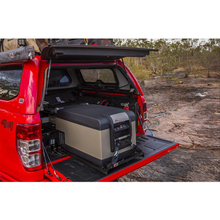 Load image into Gallery viewer, A gun-metal colored Toyota Hilux equipped with Bluetooth connectivity and an ARB Classic Series II 63 Quarts Portable Fridge Freezer Electric Powered 12V/110V 10801602 in the back.