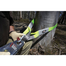 Load image into Gallery viewer, A person is using an ARB chainsaw to cut down a tree while ensuring the safety of their anchor point and using ARB Tree Protectors for protection.