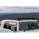 A vehicle-specific Toyota FJ Cruiser parked on a hill, equipped with an ARB Base Rack Deflector (17920040) for extra storage.