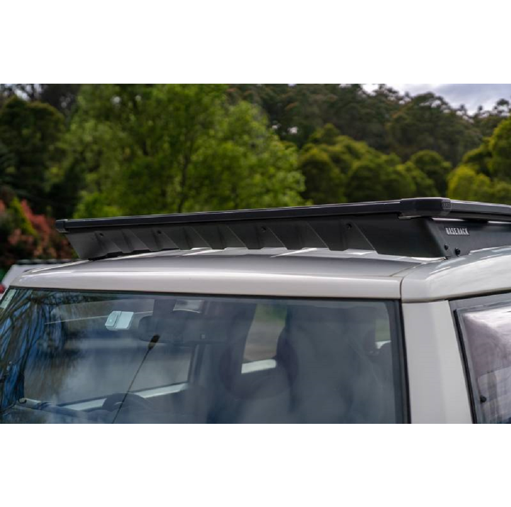 The roof of a silver SUV with an ARB Base Rack Deflector For Toyota FJ Cruiser (2007-2016) ARB 17920040 experiences wind noise.