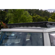 Load image into Gallery viewer, The roof of a silver SUV with an ARB Base Rack Deflector For Toyota FJ Cruiser (2007-2016) ARB 17920040 experiences wind noise.