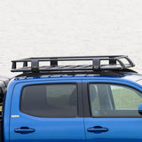 A blue Toyota Tacoma with an ARB Steel Roof Rack System for Jeep Wrangler 2018-2020 3813030KJL for cargo transportation.