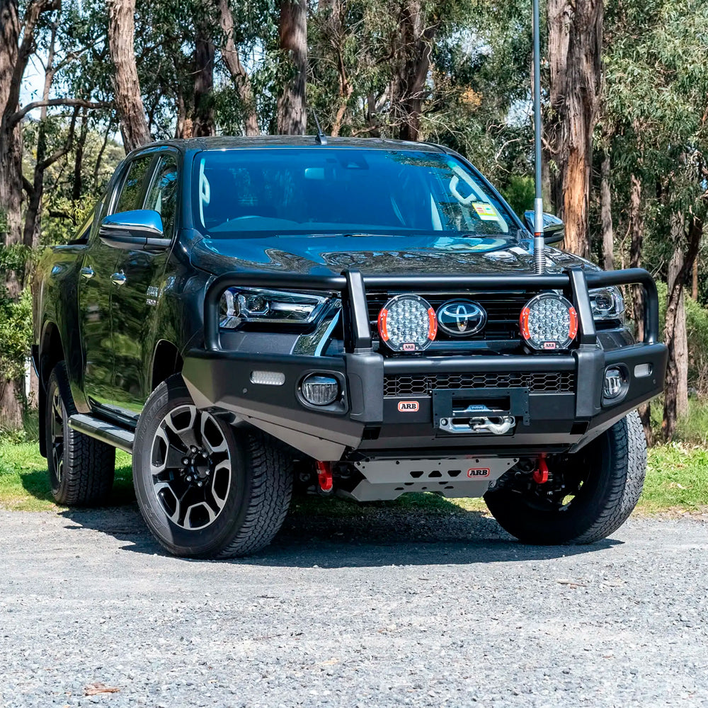 A black Old Man Emu Toyota Hilux parked on a gravel road, showcasing the comfort and control of the ARB Front Strut Top Hat Kit OMETH002 (PAIR) for Toyota Tacoma, Land Cruiser 150 Series, FJ Cruiser.