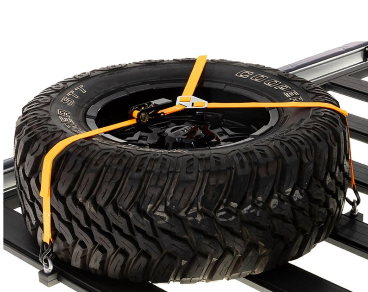 An ARB Rack Spare Wheel Y Strap 1780380 is securely fastened to a roof rack using tie-down points for cargo loading.