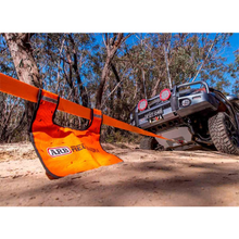 Load image into Gallery viewer, An orange strap is securely attached to a 4-wheel drive jeep on a dirt road, emphasizing safety precautions and the use of an ARB Recovery Winch Damper ARB220.