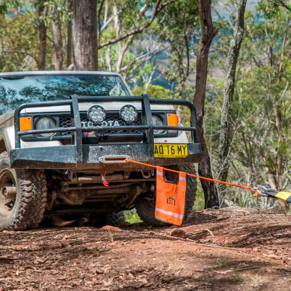 An ARB Snatch Block 7000 - 30,000lb Breaking Strength ARB2091A with a rope attached to it is parked in the woods, ready to tackle the carrying capacity needed for an adventurous trip. Equipped with roof racks, this vehicle ensures optimal SEO keywords like ARB.
