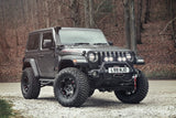 The Fox Racing Jeep Wrangler JL 2 Door Lift Kit (Medium Load) from Fox Suspension is parked in the woods, showcasing its increased ride height.