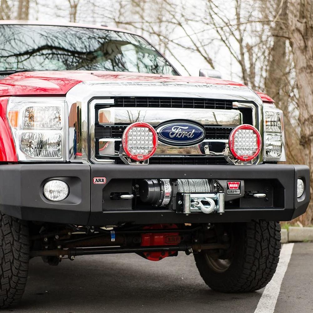 A red ARB Ford F-250 pickup truck with winch compatibility is parked in a parking lot.