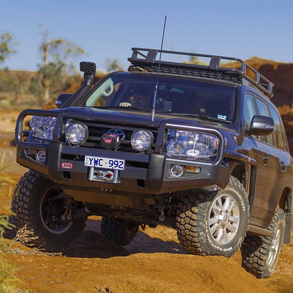 A high capacity ARB black SUV driving down a dirt road with secure storage is equipped with the Steel Basket Rack Kit 87” X 44” for Land Cruiser 200 Series 2008 - 2021 ARB 3800040KLC2.