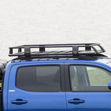 A blue ARB Toyota Tacoma with a Steel Flat Rack Kit 52” x 44” providing secure storage.