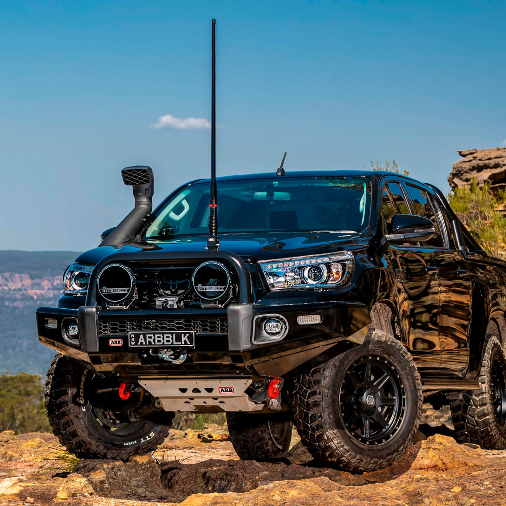 A black Old Man Emu Toyota Tacoma is parked on a rock, its ARB Front Strut Top Hat Kit OMETH002 (PAIR) ensuring control and comfort.