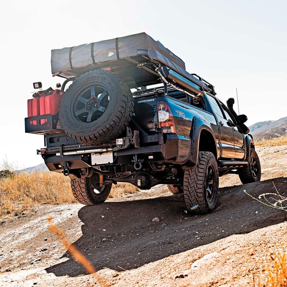 An Old Man Emu Toyota Tacoma with a camper on the back of it, equipped with compression valving.