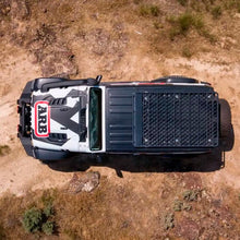 Load image into Gallery viewer, An aerial view of a Jeep JL Wrangler pickup truck on a dirt road with an ARB Roof Rack Mounting Kit Hardtop for Jeep Wrangler JL 2018-2021 ARB 3750010 installed for extra storage capacity.