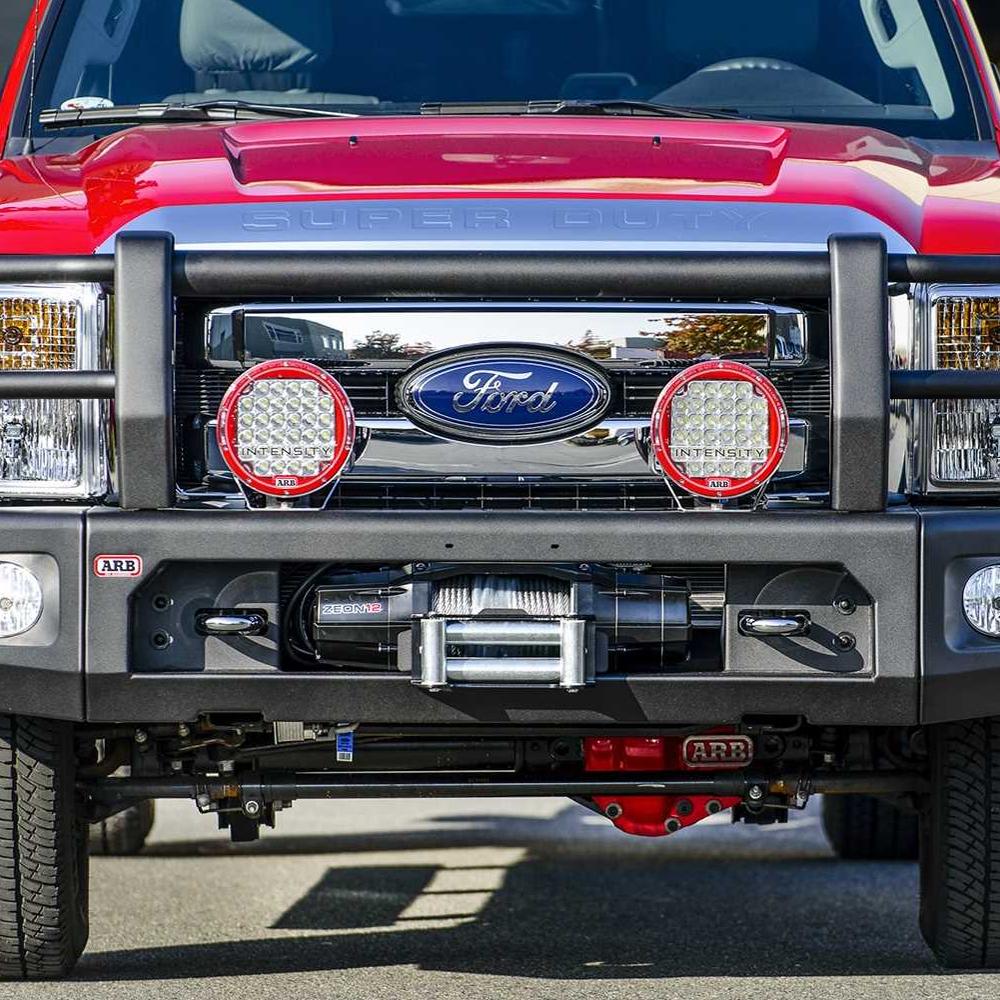 The front end of a red ARB F-250 SUPER DUTY pickup truck featuring winch compatibility and larger tubing.