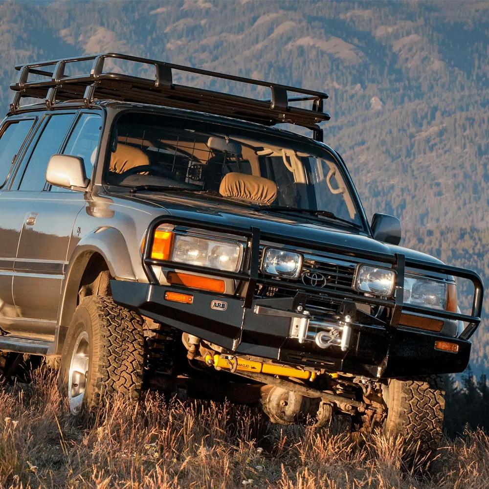 A secure storage ARB Steel Rack with Mesh Floor 43” X 49" for Jeep Cherokee XJ parked in a field with mountains in the background.