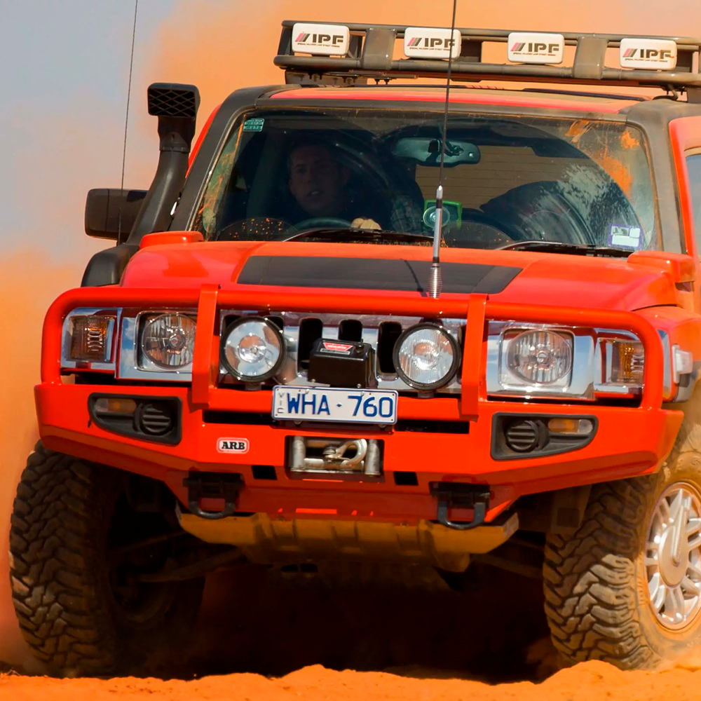A red ARB jeep with secure storage driving through sand.