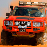 A red ARB jeep with secure storage driving through sand.