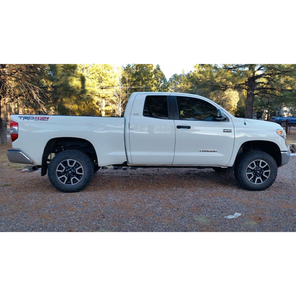 A white Old Man Emu Toyota Tundra, known for its longevity, parked in a parking lot.