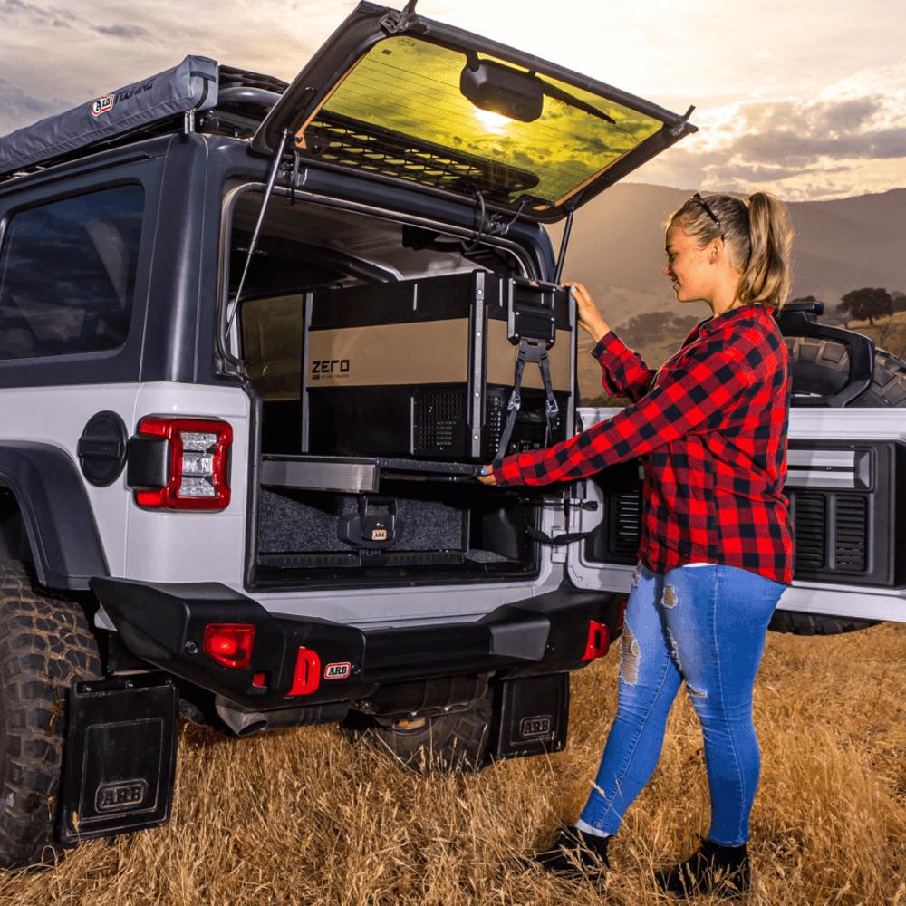 A woman opening the trunk of a jeep with ARB Cable Guide CABRUN.