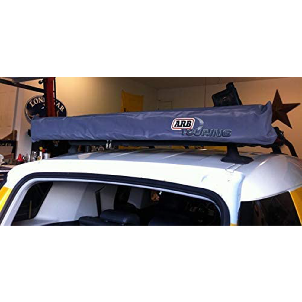 A car with an ARB Touring Awning 814301 (49.21” x 82.67”) attached to the roof rack assembly, perfect for camping trips.