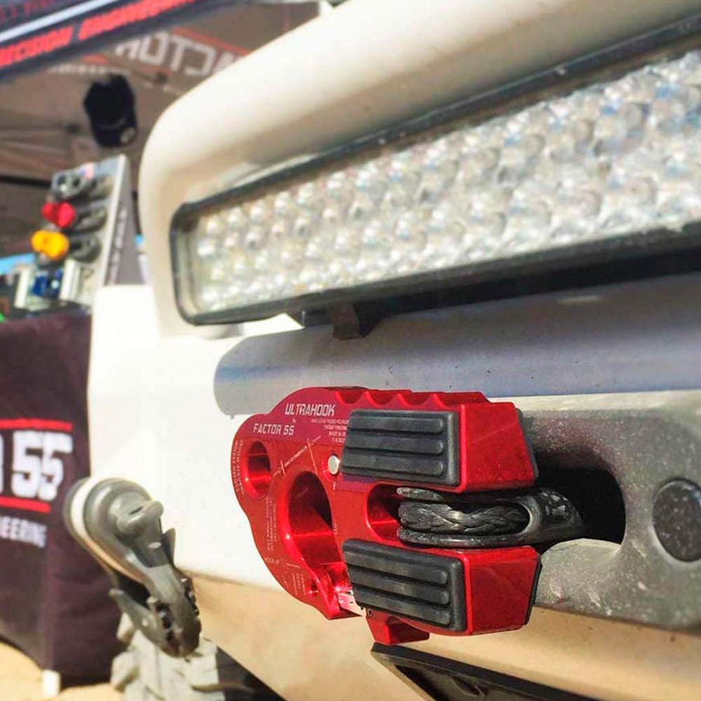 A Factor 55 UltraHook Winch Shackle Aluminum in Red 00250-01 bumper with a red LED light attached to the truck.